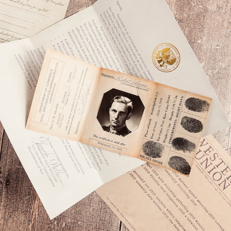 The Fifth Column materials laid out on pale wood: a folded 1945 identity certificate with a photograph and inked fingerprints, a Department of Commerce letter with a gold embossed seal, and a Western Union telegram