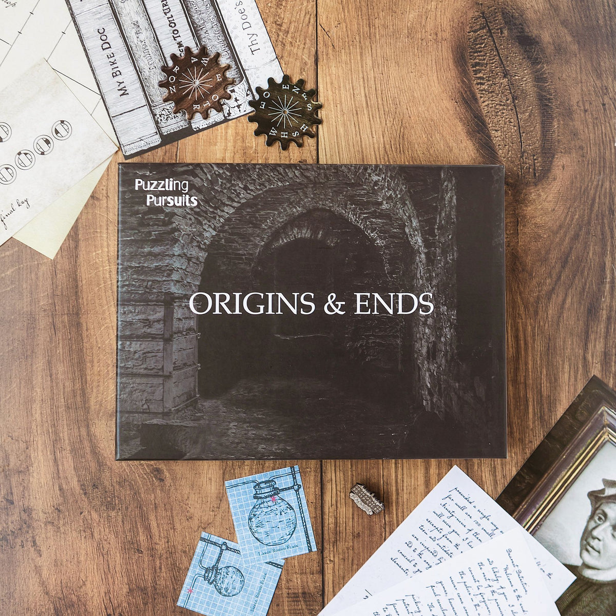 Origins and Ends game box with materials on a wooden table
