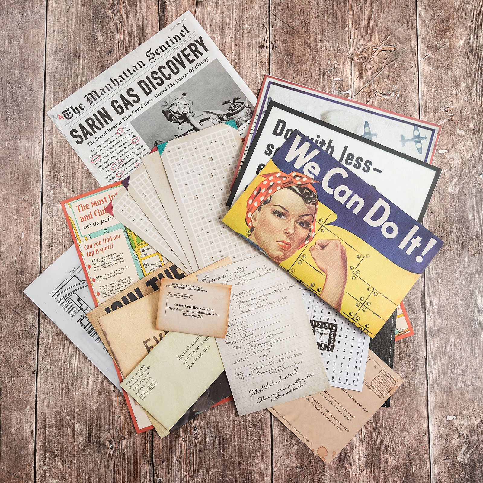 The Fifth Column materials fanned out on weathered wooden boards: a Manhattan Sentinel front page headlined Sarin Gas Discovery, a We Can Do It! poster, punched grid cards, an envelope addressed to a special agent in New York, a Civil Aeronautics Administration envelope, handwritten personal notes and a letter-grid cipher card